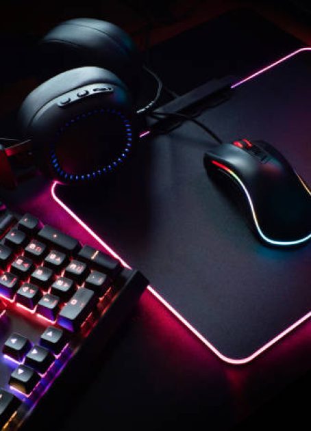 gamer workspace concept, top view a gaming gear, mouse, keyboard with RGB Color, joystick, headset, webcam, VR Headset on black table background.